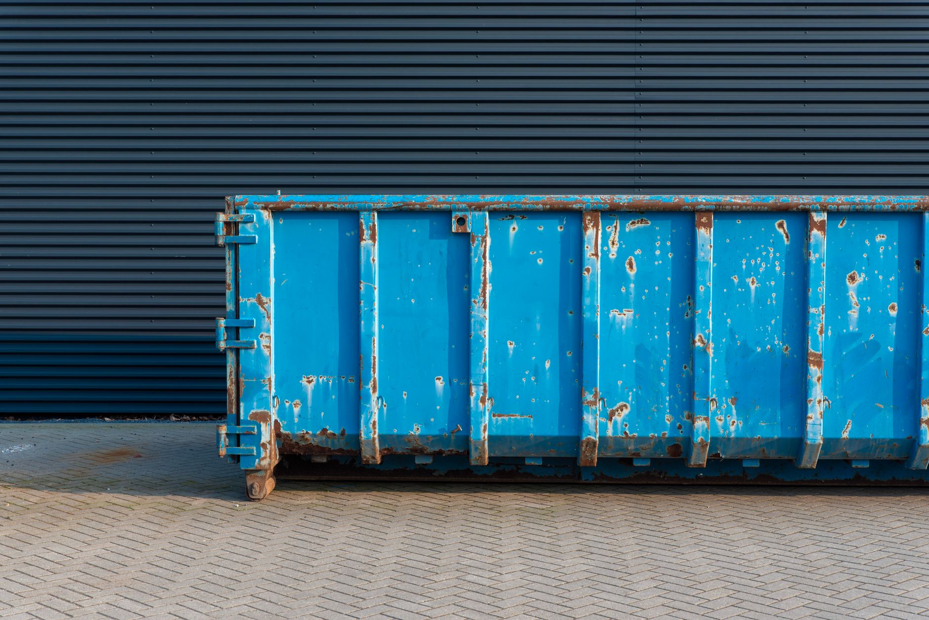 A residential driveway in a Tucson desert landscape neighborhood with a clean, professional roll-off dumpster properly